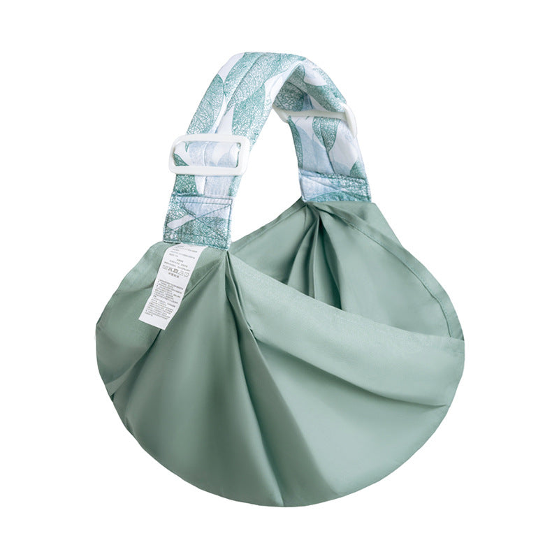 Green handbag with a patterned handle on a white background mesh baby carrier bleu ribbon baby