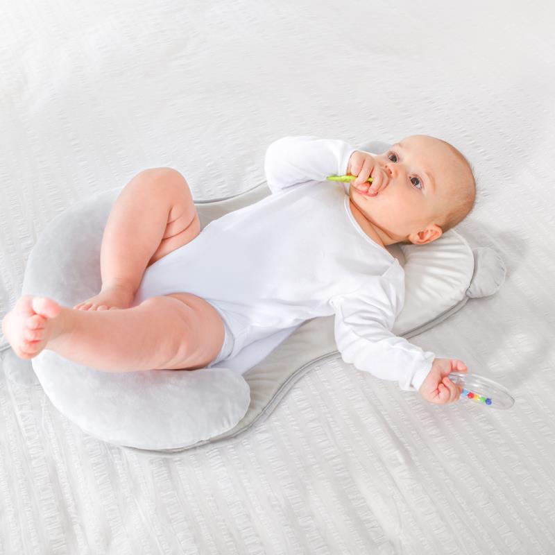 Baby lying on a white cushion with a colorful toy, on a light gray background Baby Head Shaping Pillow Anti-Flat Head Support Cushion