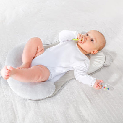 Baby lying on a white cushion with a colorful toy, on a light gray background Baby Head Shaping Pillow Anti-Flat Head Support Cushion