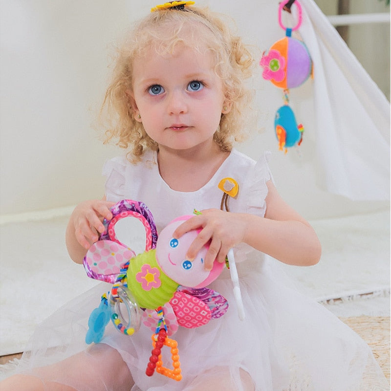 Child playing with a colorful baby toy in a soft, blurred background Baby Stroller & Crib Toy Hanging Plush Sensory Animals bleu ribbon