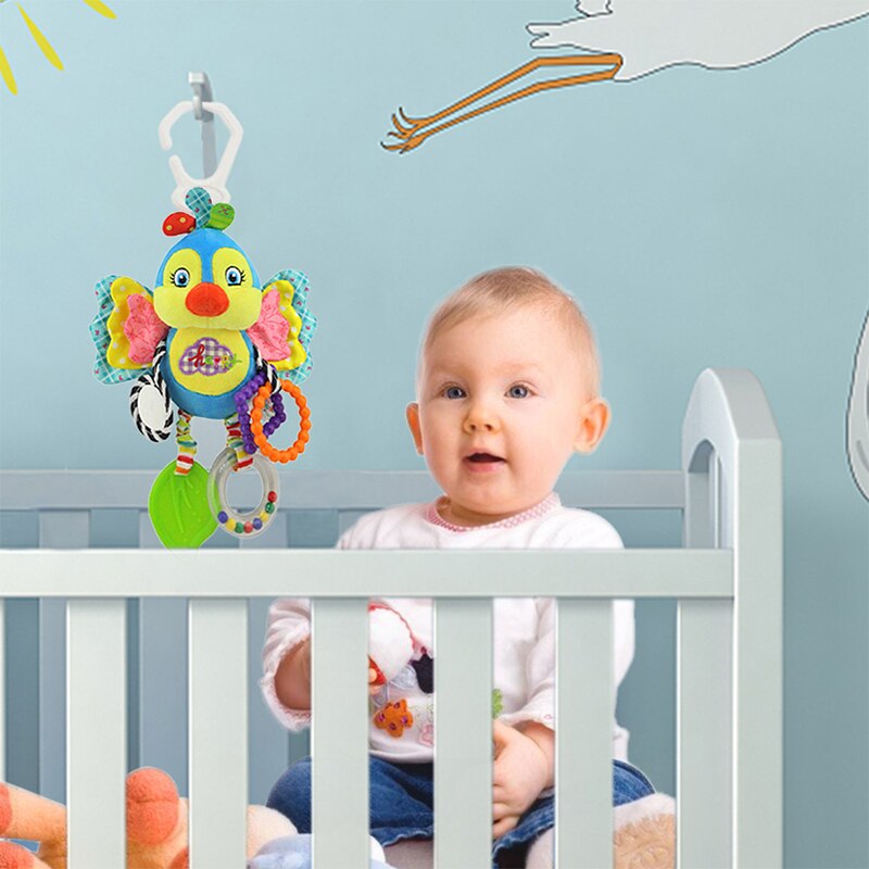 Baby in a crib with a colorful fish-shaped toy hanging above Baby Stroller & Crib Toy Hanging Plush Sensory Animals bleu ribbon