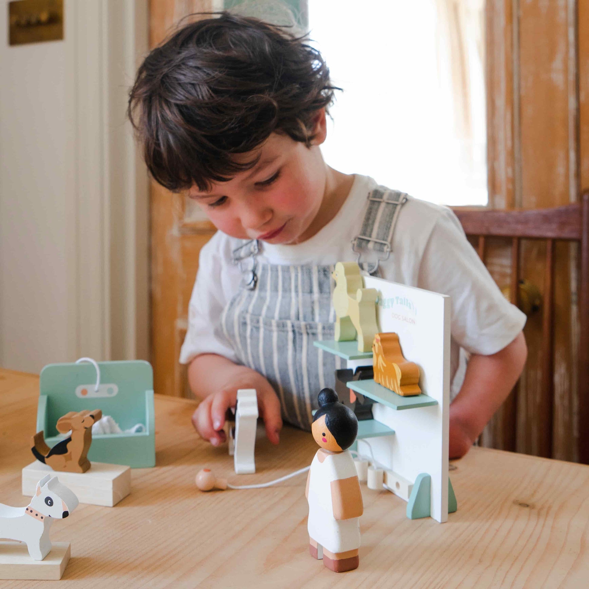 Child playing with wooden toys on a table. Waggy Tails Dog Salon by Tender Leaf Toys - Wooden dog grooming set with 7 breeds