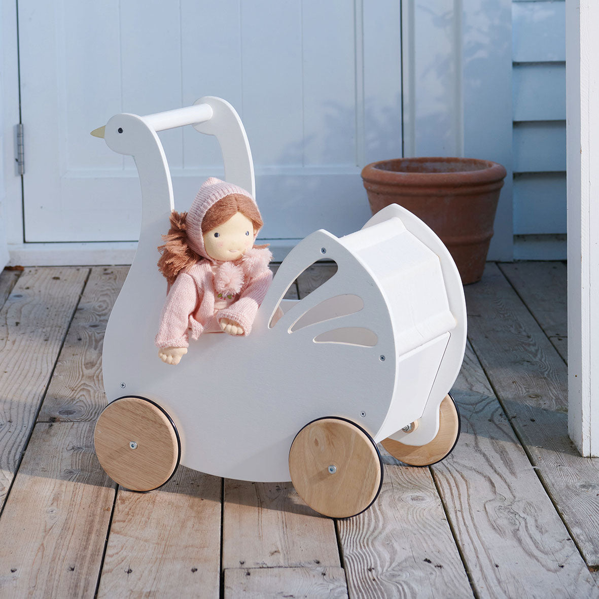 Wooden goose-shaped pram with a doll on a wooden deck. Liselie Doll by ThreadBear Design - Waldorf-style textile ragdoll in gift box