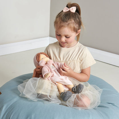 Young girl holding a doll on a blue cushion.Liselie Doll by ThreadBear Design - Waldorf-style textile ragdoll in gift box
