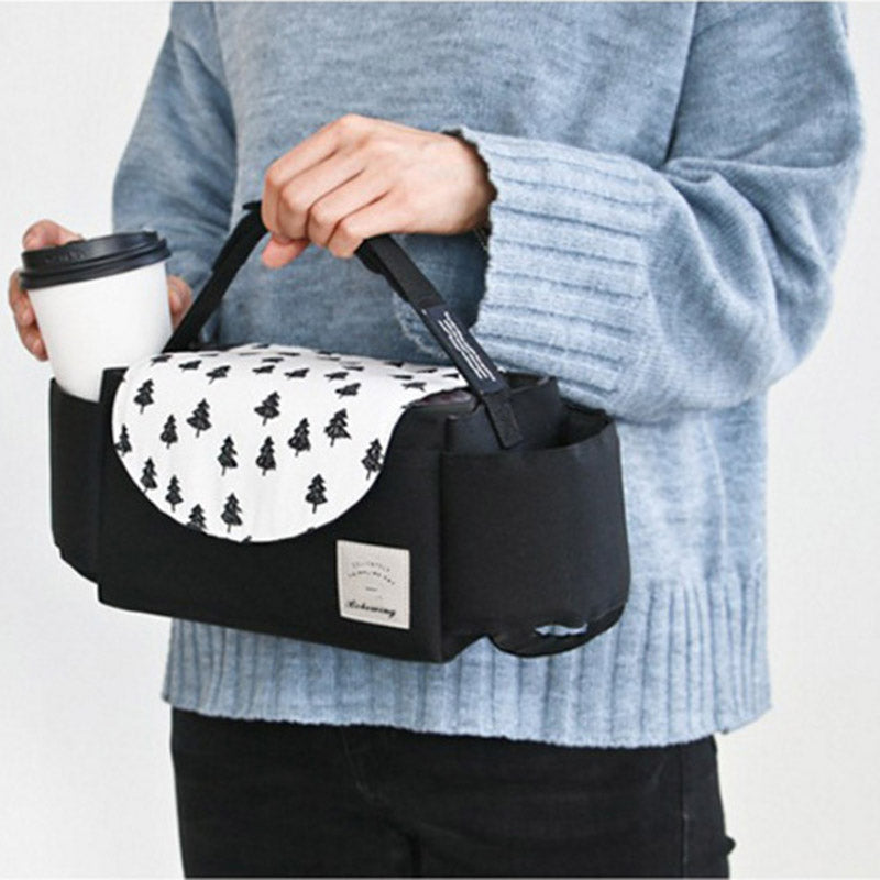 Person holding a black bag with a white patterned flap, wearing a light blue sweater. bleu ribbon