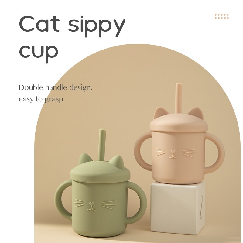 Two cat-shaped sippy cups, one green and one pink, on a beige background. bleu ribbon baby