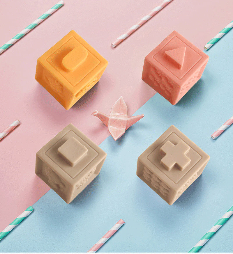 Four square-shaped soap bars in different colors on a pink and blue background with straws. bleu ribbon