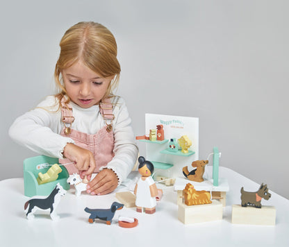 Child playing with wooden toys on a white surface. Waggy Tails Dog Salon by Tender Leaf Toys - Wooden dog grooming set with 7 breeds