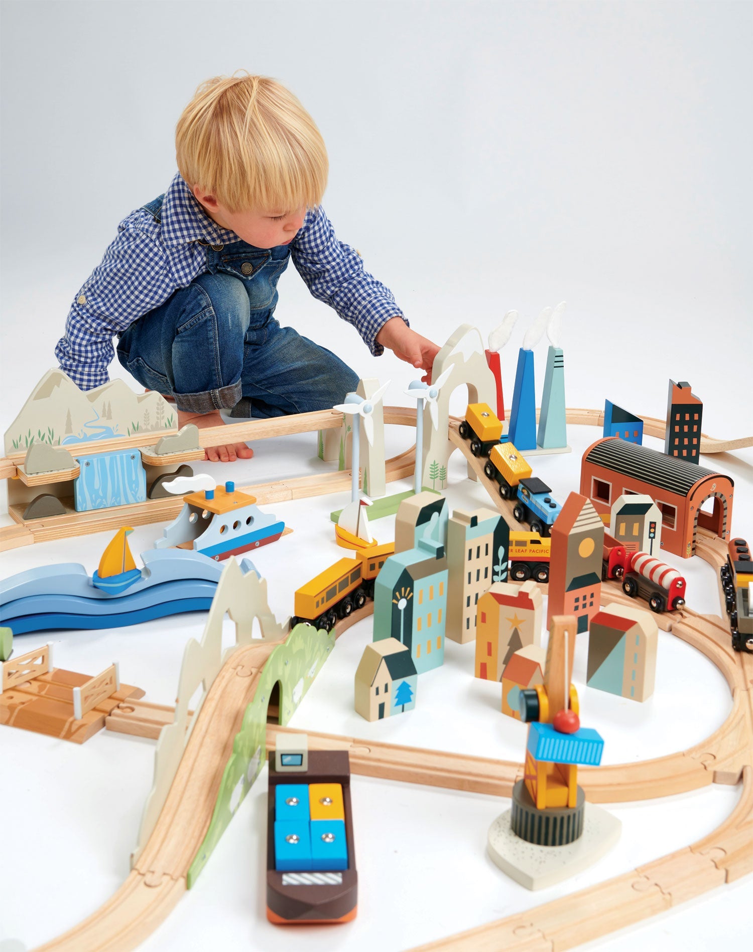 Child playing with a wooden train set on a white background Mountain View Wooden Train Set 58-piece set by Tender Leaf Toys