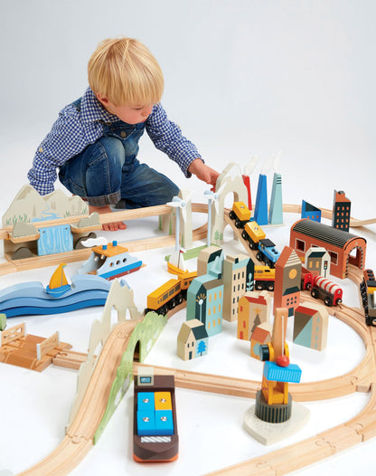 Child playing with a wooden train set on a white background Mountain View Wooden Train Set 58-piece set by Tender Leaf Toys