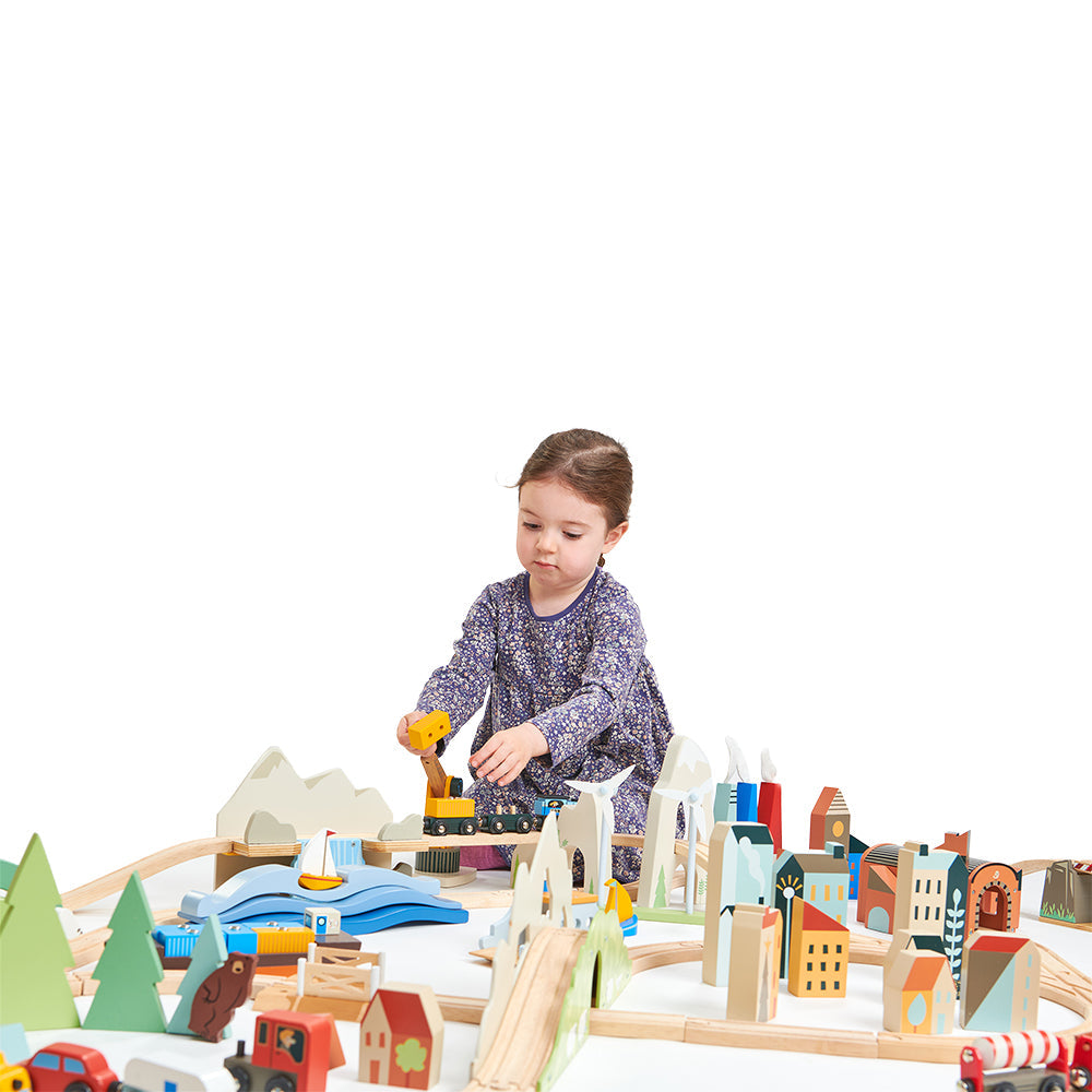 Child playing with a wooden toy set on a white background Mountain View Wooden Train Set 58-piece set by Tender Leaf Toys