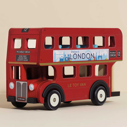 Red toy double-decker bus with 'Welcome to London' sign on a beige background. London Wooden Bus by Le Toy Van