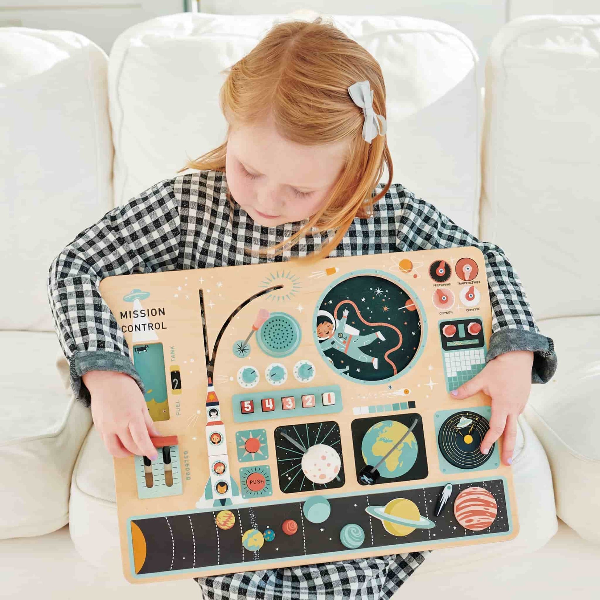 A toddler engaging in sensory play with the Space Station busy board in a Montessori nursery setting
