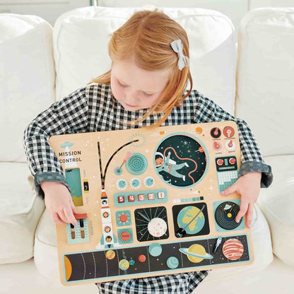 A toddler engaging in sensory play with the Space Station busy board in a Montessori nursery setting