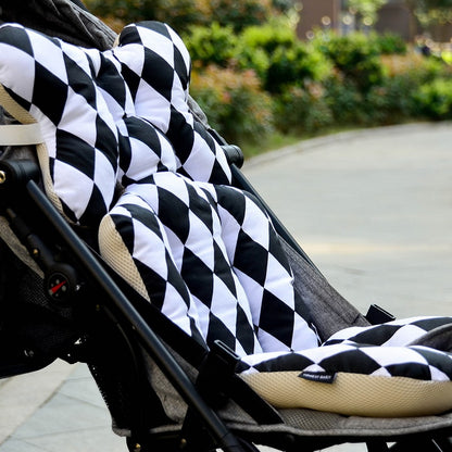 Black and white checkered cover on a stroller seat with a blurred outdoor background bleu ribbon