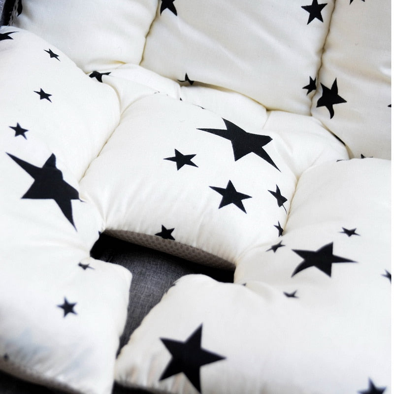 White cushions with black star patterns arranged in a circular pattern. bleu ribbon