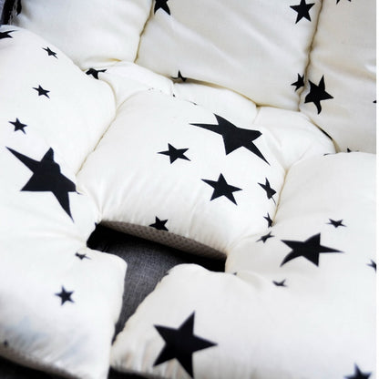 White cushions with black star patterns arranged in a circular pattern. bleu ribbon