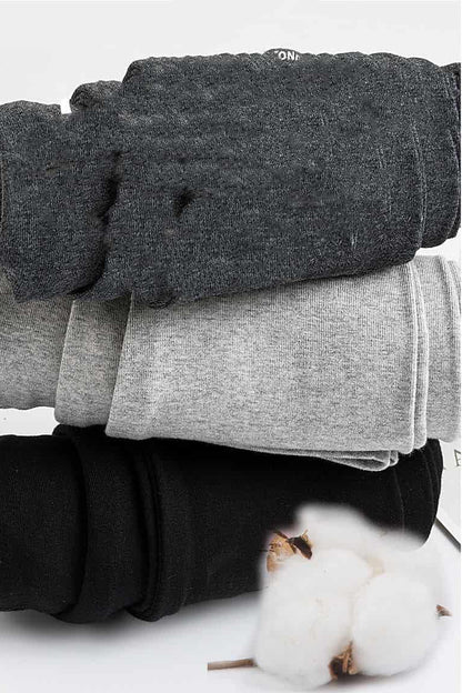 Stack of folded gray and black pants with a cotton plant in the corner on a white background. bleu ribbon