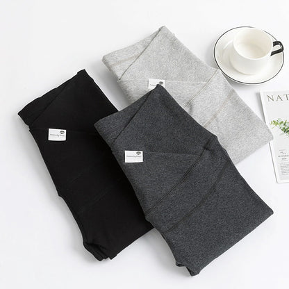Three folded sweatpants in black, gray, and light gray on a white surface with a cup and saucer. bleu ribbon