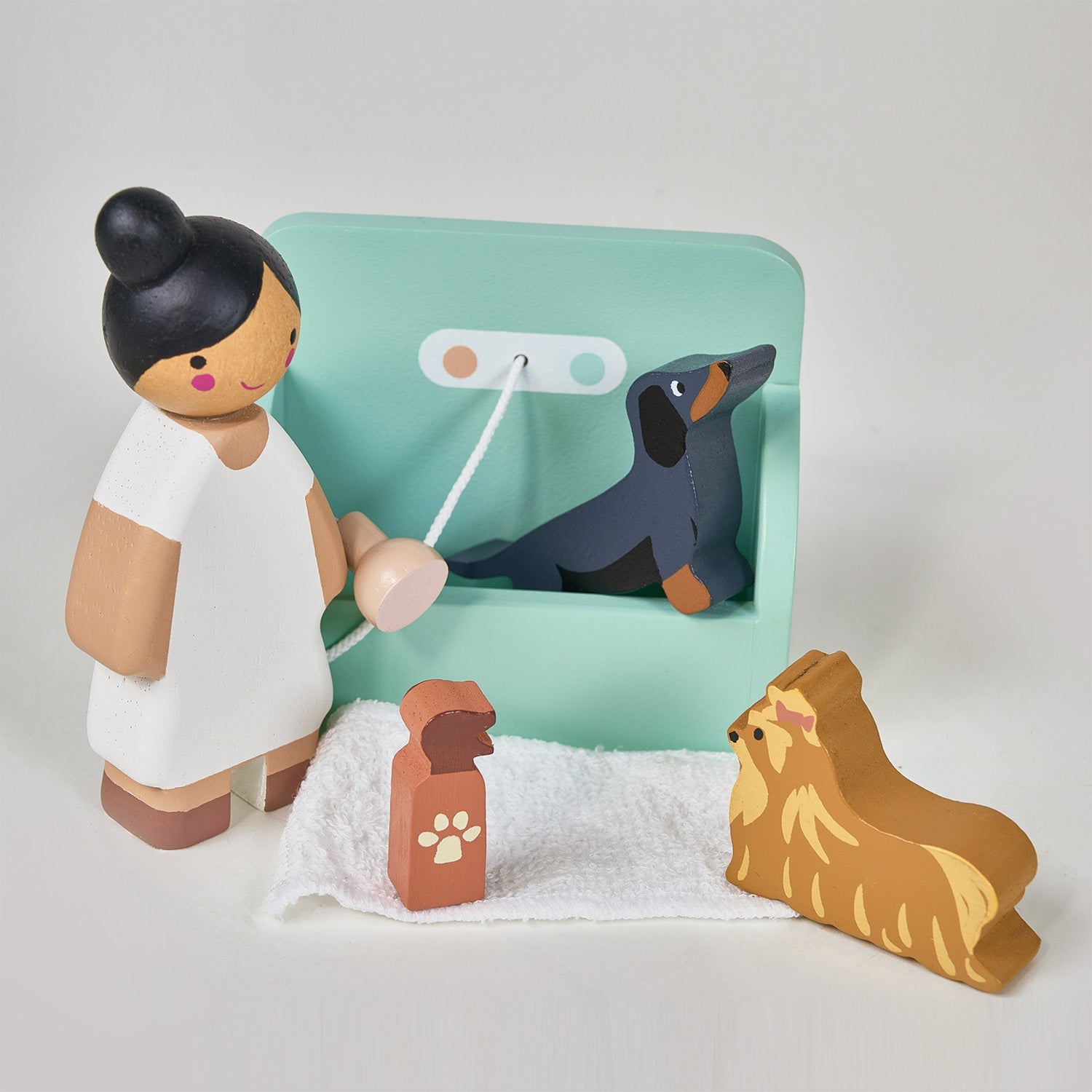 Wooden toy figure of a person with a dog and a leash on a light gray background. Waggy Tails Dog Salon by Tender Leaf Toys - Wooden dog grooming set with 7 breeds