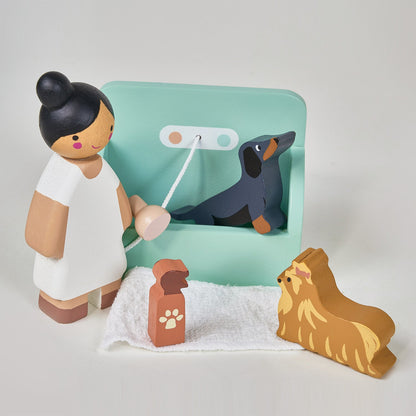 Wooden toy figure of a person with a dog and a leash on a light gray background. Waggy Tails Dog Salon by Tender Leaf Toys - Wooden dog grooming set with 7 breeds