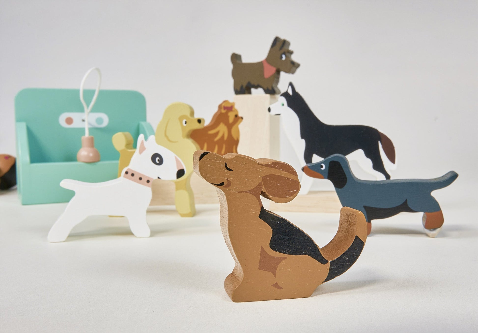 Set of colorful dog-shaped wooden toys on a white background. Waggy Tails Dog Salon by Tender Leaf Toys - Wooden dog grooming set with 7 breeds