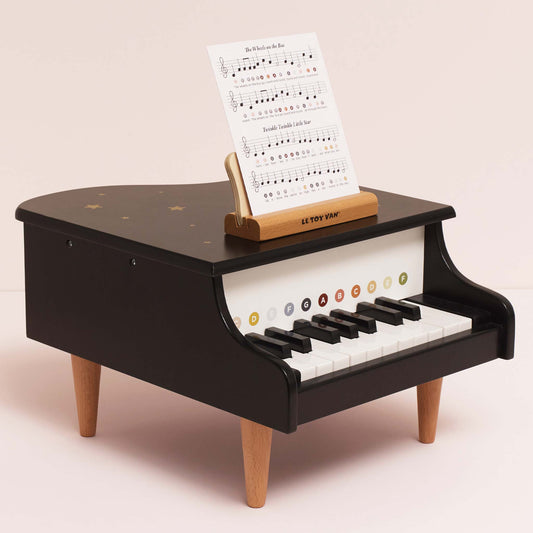 Wooden Grand Piano Toy by Le Toy Van - Luxury black toy piano with wooden legs on a light pink background