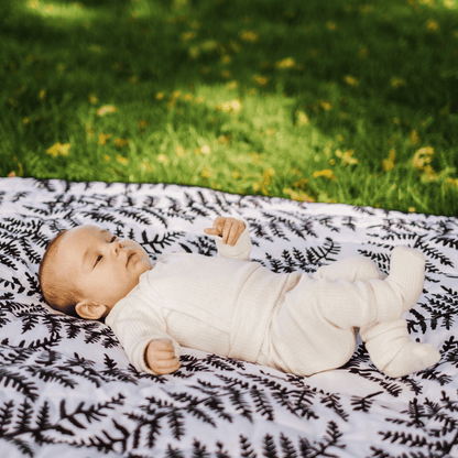 Close-up of a baby resting on the Etta Loves fern print outdoor playmat, benefiting from the visually stimulating and calming design.