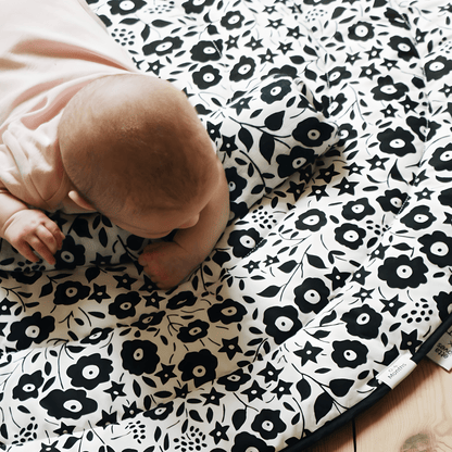 A baby practicing tummy time on the black and white Etta Loves x Liberty sensory playmat, utilizing the pattern to build neck strength and visual focus.