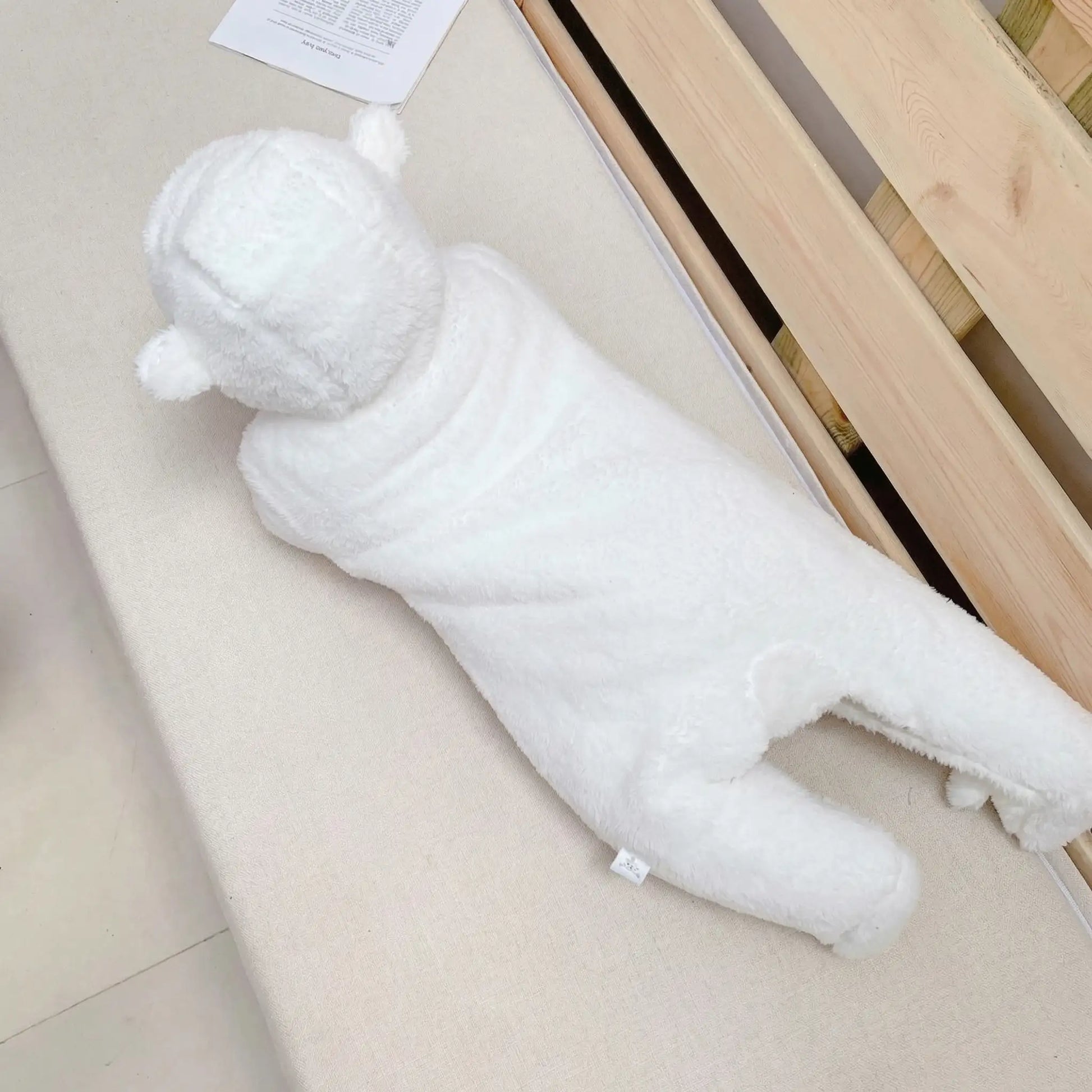 BleuRibbon Baby Winter Jumpsuit – Shu Cotton Velvet Romper​. White plush toy resembling a bear on a light-colored floor.