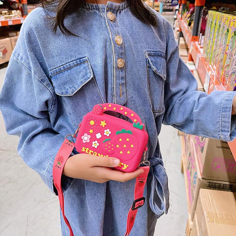 Person holding a pink strawberry-shaped bag in a store setting bleu ribbon baby