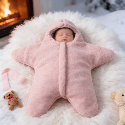 Newborn baby sleeping in pink starfish-shaped cashmere blend winter swaddle. Warm and cozy fleece sleeping sack for infants.