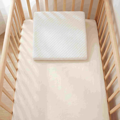 Top-down view of BleuRibbon memory foam wedge pillow placed inside a standard baby crib. Universal fit design for cribs and bassinets to help babies sleep better.