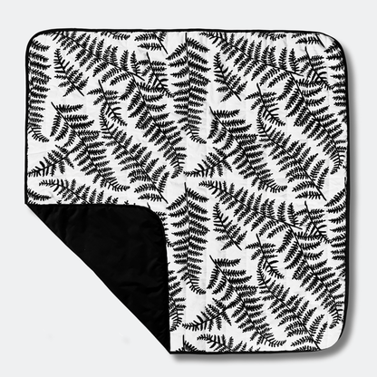 Etta Loves outdoor playmat featuring the black and white sensory fern print, with a folded corner revealing the durable, water-resistant black base.