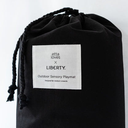 The premium black canvas drawstring carry bag featuring the Etta Loves x Liberty London co-branded label, designed for easy travel with the outdoor playmat.