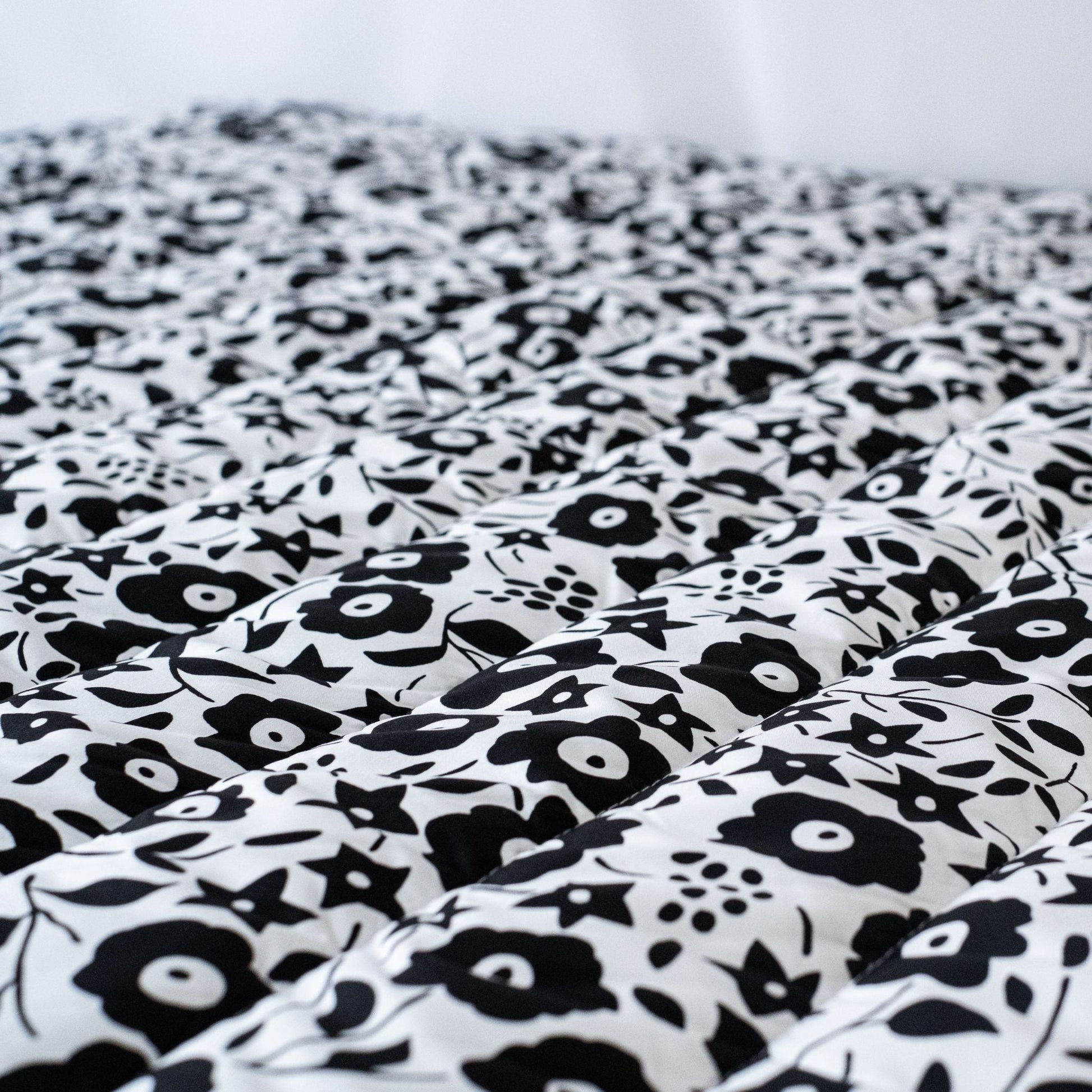 Close-up of the softly padded, high-contrast black and white Liberty London floral pattern on the Etta Loves sensory outdoor playmat.