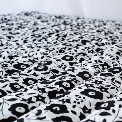 Close-up of the softly padded, high-contrast black and white Liberty London floral pattern on the Etta Loves sensory outdoor playmat.