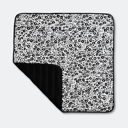 Full top view of the Etta Loves x Liberty outdoor sensory playmat, featuring a folded corner that reveals its practical, water-resistant black base.
