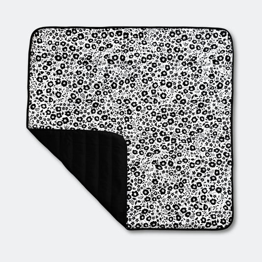 Full top view of the Etta Loves x Liberty outdoor sensory playmat, featuring a folded corner that reveals its practical, water-resistant black base.