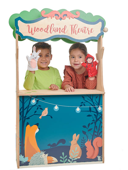 Children playing with a 'Woodland Theatre' toy set, featuring animal illustrations on the side. Puppet theatre side featuring red curtains, acorn chalkboard, and included glove puppets.