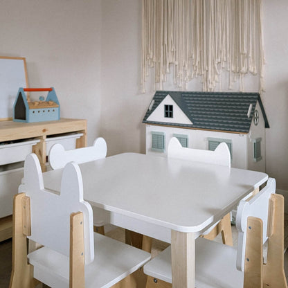 Children's table and chairs set with a dollhouse in a room setting. Classic wooden nursery table for four children group play