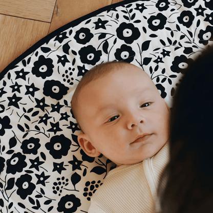 A calm newborn baby lying on the black and white Etta Loves x Liberty sensory playmat, demonstrating the soothing effect of science-backed visual patterns.