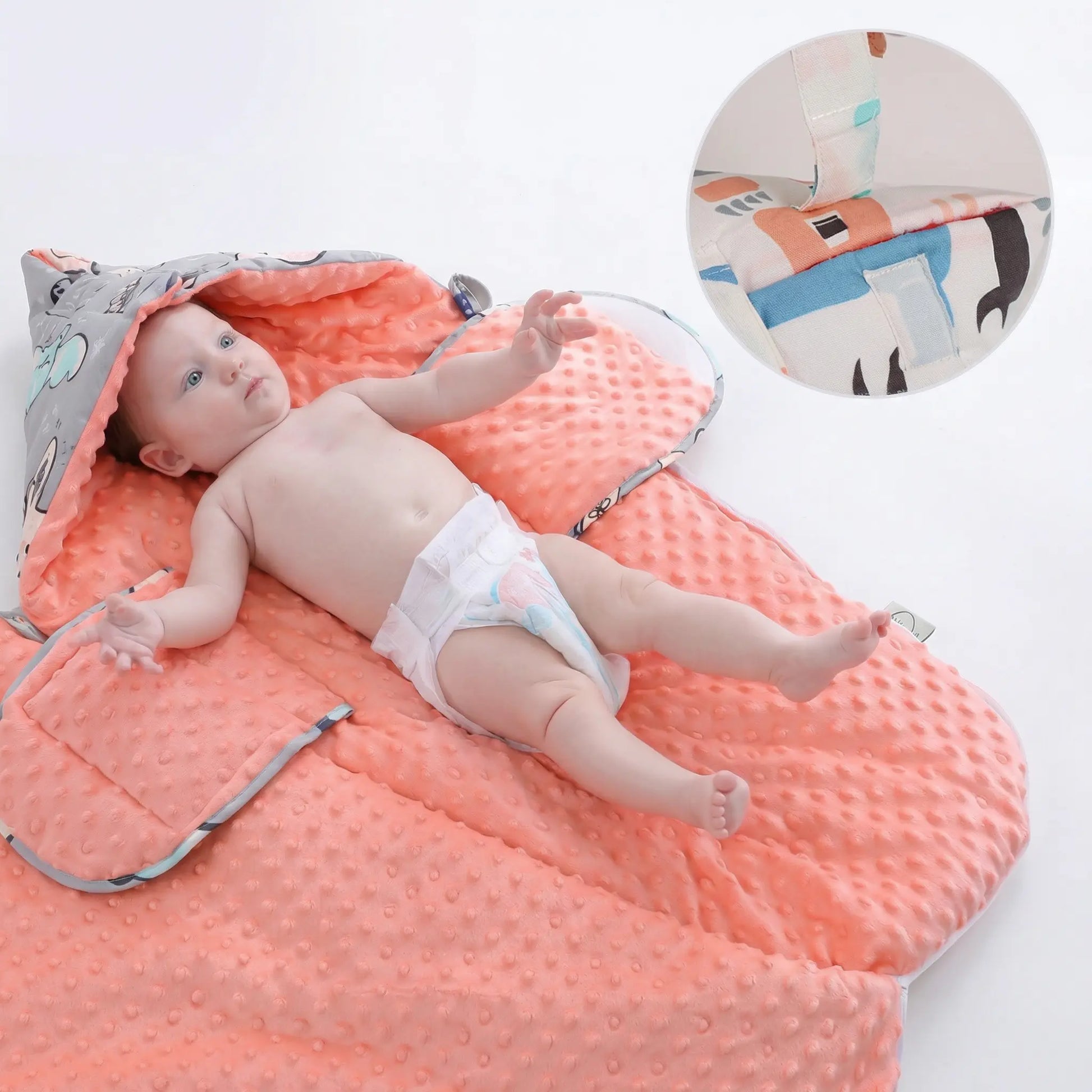 BleuRibbon Baby fleece stroller quilt with hood. Baby lying on a pink quilt with a small pillow, on a white background