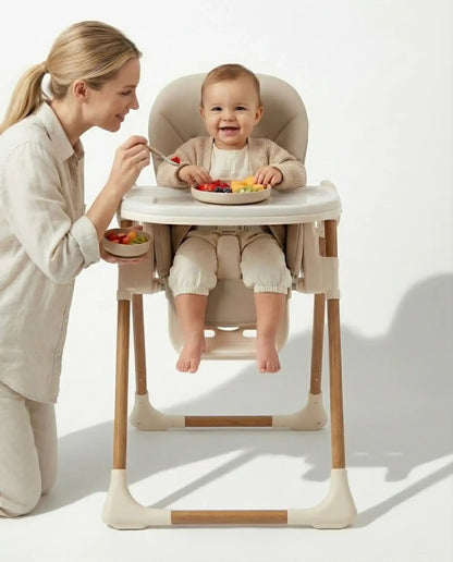 Woman feeding a baby in Venture Flare Highchair in Beige with adjustable height and wooden accents with a white background