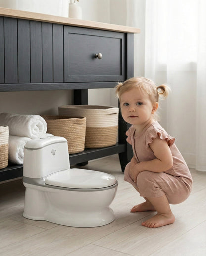 Venture Realistic Training Potty in Grey with flushing sounds and lights. Child in a bathroom with a toilet and storage shelves.