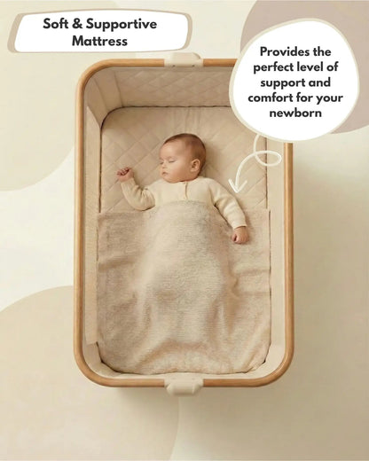 Baby sleeping in Venture Sona Bedside Crib in Beige for newborns. with a soft and supportive mattress, text indicating comfort for newborn